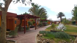 Elifaz Desert Experience Holiday في إليباز: فناء به طاولات وكراسي في حديقة