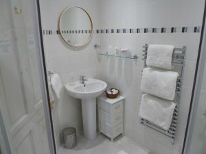 a white bathroom with a sink and a mirror at Failte Bed & Breakfast in Oban