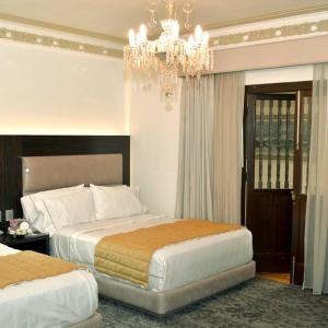 a hotel room with two beds and a chandelier at Mansion de los Abuelos in Atlacomulco de Fabela