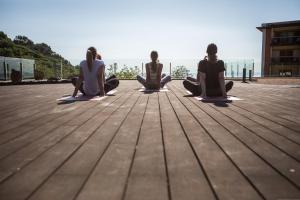 four women sitting in a yoga pose on a wooden floor at Hotel Santa Marta in Lloret de Mar