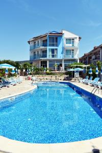 a swimming pool with chairs and a building in the background at Nushev Hotel in Sveti Vlas