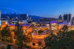 une ville illuminée la nuit avec des bâtiments dans l'établissement DeLuxe PLAZA, à Almaty