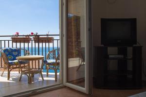 a balcony with a television and a table and chairs at Villa Palma Ceoce in Budva