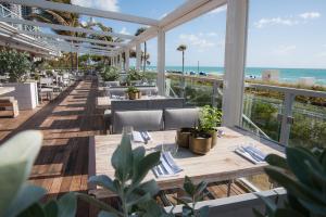 a patio area with chairs, tables, and umbrellas at Eden Roc Miami Beach in Miami Beach