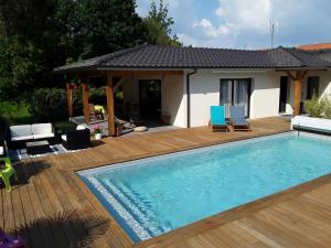 a swimming pool with a wooden deck and a house at Chambre d'hôtes les Iris à Mios sur le Bassin d'Arcachon in Mios