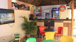 un restaurante con un bar con sillas rojas y amarillas en Chantella Suites en Ikeja