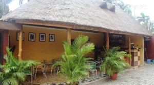 a building with a grass roof with tables and chairs at Chantella Suites in Ikeja