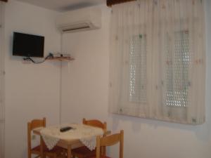 een eetkamer met een tafel en een tv aan de muur bij Apartmani i soba Mia Poreč in Poreč