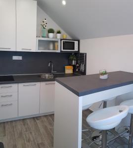 a kitchen with white cabinets and a black counter top at Apartment Prijeboj Plitvice Lakes in Prijeboj