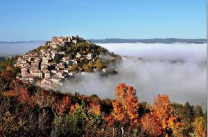 una piccola città su una collina nella nebbia di Les Trois Hiboux a Crespin