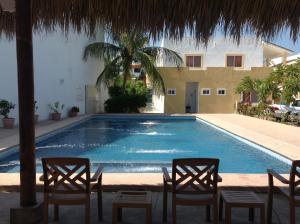 ein Schwimmbecken mit zwei Stühlen und ein Gebäude in der Unterkunft Condominios JAROJE Huatulco in Santa Cruz Huatulco