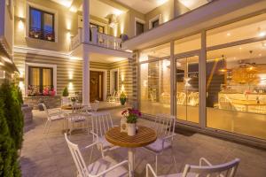 d'une terrasse avec des chaises blanches, des tables et des fenêtres. dans l'établissement Villa Ester, à Korçë