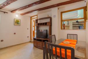 a dining room with a table and a television at Apartment Rialto with private parking in Cres