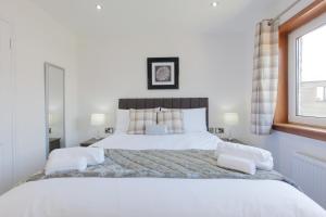 een slaapkamer met een groot bed met witte lakens en kussens bij Leys Park Executive Apartments in Dunfermline