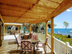 eine Holzterrasse mit einem Tisch und Stühlen in der Unterkunft Sea Parrot Ocean View Manor in Indian Brook