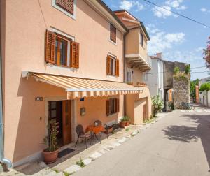 ein Haus mit einem Tisch und Stühlen außerhalb davon in der Unterkunft Apartment Rialto in Cres