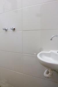 La salle de bains est pourvue d'un lavabo et d'un mur carrelé blanc. dans l'établissement Vhostel, à Uberlândia