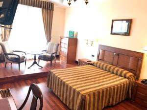 a bedroom with a bed and chairs in a room at Hotel Begoña Park in Gijón
