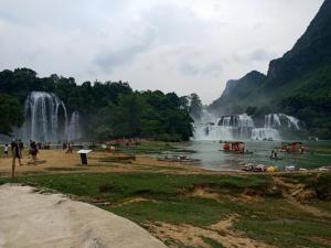 um grupo de pessoas numa praia em frente à cascata em Nhà Nghỉ Kiều Thanh Nguyệt - Bản Giốc em Dam Thuy