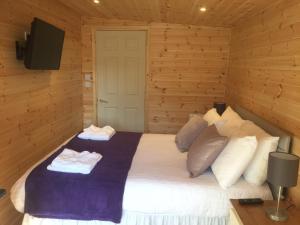 a bedroom with a bed with two towels on it at Romantic Getaway Luxury Wooden Cabin With Private Hot Tub and BBQ in Aberystwyth