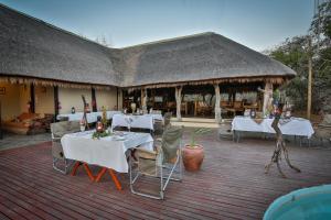 ein Restaurant mit weißen Tischen und Stühlen auf einer Terrasse in der Unterkunft Tangala Safari Camp in Thornybush Game Reserve