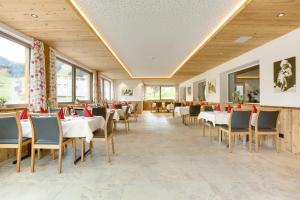 una sala da pranzo con tavoli, sedie e finestre di Hotel Burtschahof a Bürserberg