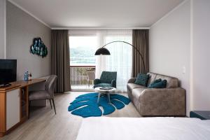 a bedroom with a bed and a desk and a couch at Seehotel Vinzenz in Velden am Wörthersee
