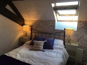 a bedroom with a bed with blue pillows and a window at Stoneleigh Barn Bed and Breakfast in Sherborne