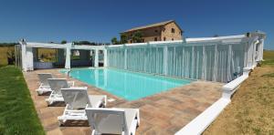 a swimming pool with chairs and a building at villa Resort Tre Castelli in Trecastelli