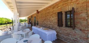 a patio with white tables and chairs and a brick wall at villa Resort Tre Castelli in Trecastelli