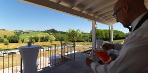 Un uomo in piedi su un portico con vista su un campo di villa Resort Tre Castelli a Ripe