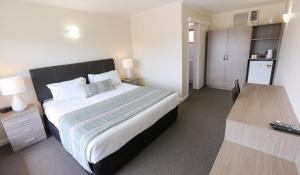 a bedroom with a large bed and a kitchen at Seven Pines Motor Inn in Mildura