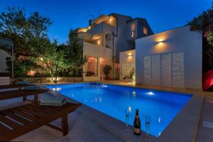 a swimming pool in front of a house at night at Apartment Mediteraneo in Makarska