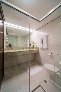 y baño con ducha de cristal y aseo. en Hotel Panamby São Paulo en São Paulo