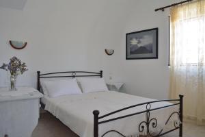 a bedroom with a bed with white sheets and a window at Volta Stonehouse Apartments in Frátsia