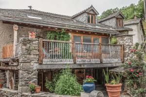 a stone house with a balcony with potted plants at The Dragon Barn - Studio in Ascou