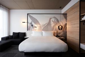 ブロサールにあるHôtel Escad Quartier DIX30の大きな白いベッドとソファのある寝室