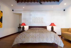 a bedroom with a bed and two lamps and a couch at Ellora Villa in Sanur