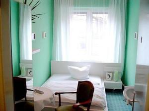 a green room with a bed and a window at Hotel Neustadt in Osnabrück
