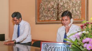 two men sitting at a table talking on a phone at Oak Ray Serene Garden Hotel in Kandy