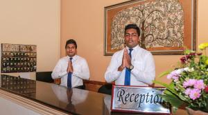 Dois homens de gravata estão sentados numa mesa. em Oak Ray Serene Garden Hotel em Kandy