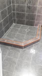 a bench in a shower with a tile floor at gostevoi dom in Zugdidi