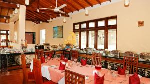 un restaurante con una mesa larga con servilletas rojas en Oak Ray Serene Garden Hotel, en Kandy