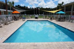 una gran piscina azul con sillas y sombrillas en Smart Stay Inn - Saint Augustine en St. Augustine