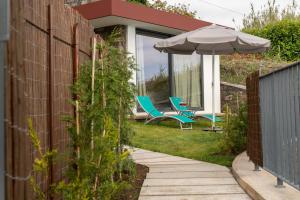 a garden with two chairs and an umbrella at Casa Melinho Lotus in Calheta