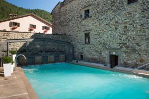 a large swimming pool in front of a stone building at Hotel Delle Terme Santa Agnese in Bagno di Romagna