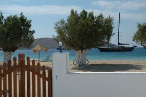 a fence and trees on a beach with a boat at Studios Αγκυρα in Livadion