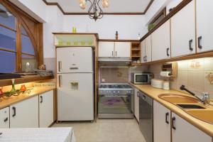 kuchnia z białymi szafkami i lodówką w obiekcie Haraki Sea View Luxury House w mieście Rodos