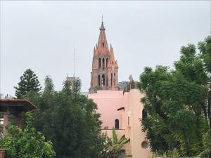 a church with a steeple in the background with trees at Casa Antaña in San Miguel de Allende