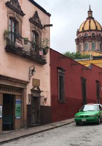 a green car parked on a street next to buildings at Casa Antaña in San Miguel de Allende